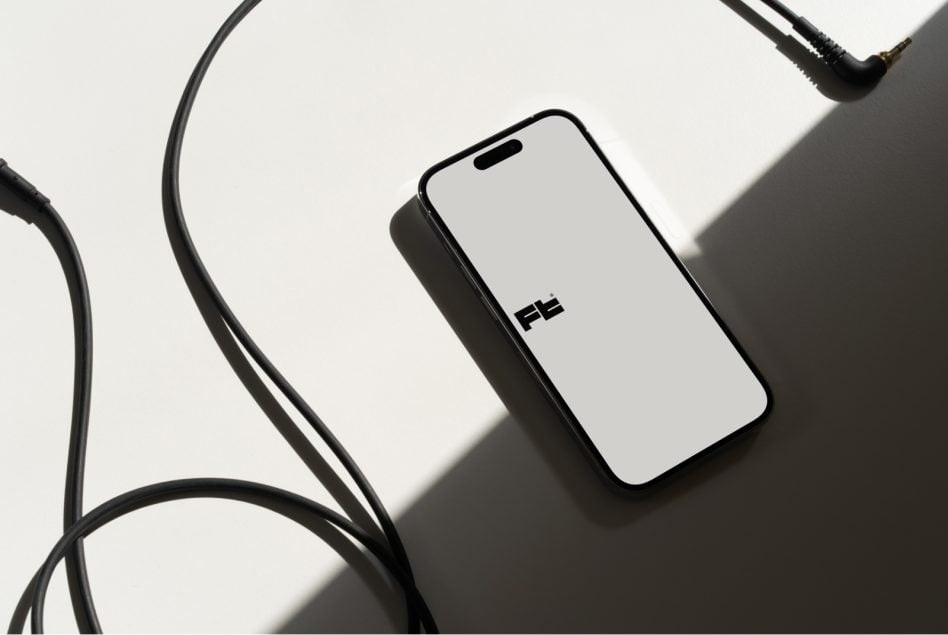 Smartphone mockup surrounded by black charging cables on white surface